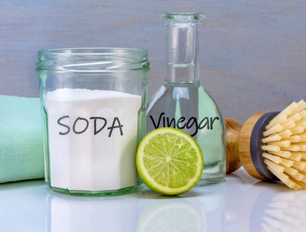 Close up image of various cleaning solutions, including bicarbonate of soda, white vinegar and a lime